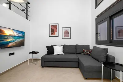 a living room with a gray couch in a white wall at San Marino Luxury Suites #2 in Asgourou