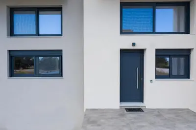 a white house with a blue door and windows at San Marino Luxury Suites #2 in Asgourou