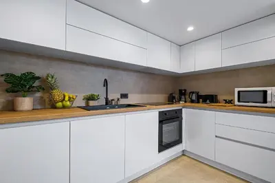a white kitchen with white cabinets and a microwave at San Marino Luxury Suites #2 in Asgourou