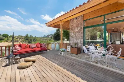 a wooden deck with a red couch and tables and chairs at 4 BD Luxurious villa with swimming pool in Sálakos