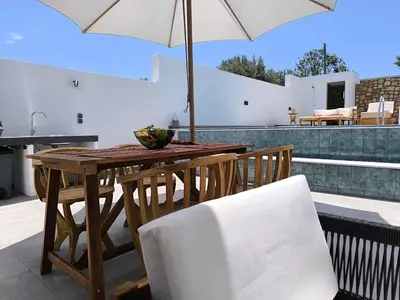 a wooden table and chairs with an umbrella on a patio at Valantina's & Mannouel Lardos Luxury Villas in Lardos