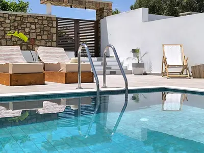 a swimming pool with two chairs next to a house at Valantina's & Mannouel Lardos Luxury Villas in Lardos