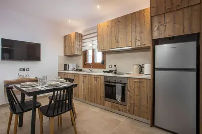 a kitchen with a table with chairs and a refrigerator at M&E APARTMENTS New in Haraki