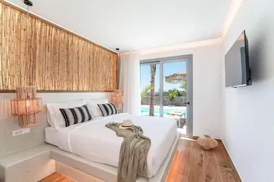 a bedroom with a white bed and a television at Villa Iviskus in Gennadi