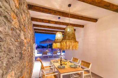 a dining room with a table and a stone wall at Villa Iviskus in Gennadi