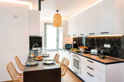 a kitchen with white cabinets and a black counter top at Villa Paparouna in Gennadi