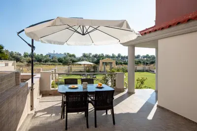 a table and chairs with an umbrella on a patio at Katerina Apartment in Afantou