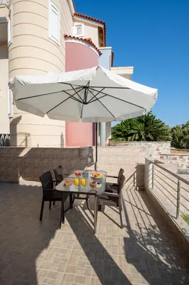 a table and chairs with an umbrella on a patio at Katerina Apartment in Afantou