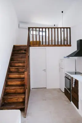 a kitchen with a staircase leading up to a loft at 1919's Studio in Asklipiḯon