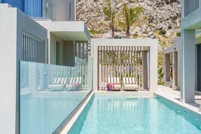 a swimming pool with two chairs and a fence at Villa Ouranos in Kiotari