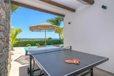a ping pong table in a patio with an umbrella at Villa Elia Gennadi in Gennadi