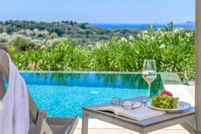 a table with a glass of wine and a plate of fruit at Massari Hills Villa 8 in Malona Village