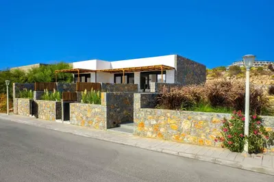 a house on the side of a street with a stone wall at Villa Kiotari Sun in Kiotari