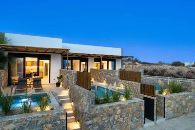 a house with a stone wall and a swimming pool at Villa Kiotari Sun in Kiotari