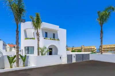 a white house with palm trees in the background at Villa Filia in Ialyssos