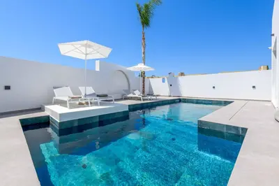 a swimming pool with a table and chairs and a palm tree at Villa Filia in Ialyssos