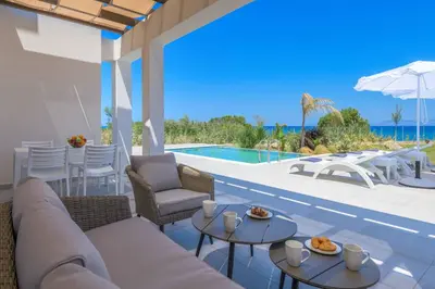 a patio with a couch and tables and a pool at Villa Panaxia Votsalo in Theologos