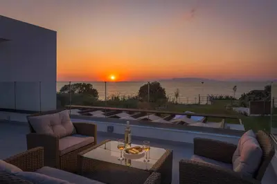 a patio with a view of the ocean at sunset at Villa Panaxia Votsalo in Theologos