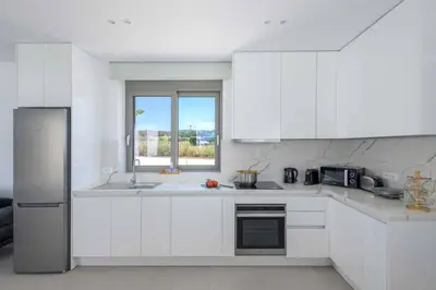 a white kitchen with white cabinets and a window at Villa Panaxia Votsalo in Theologos