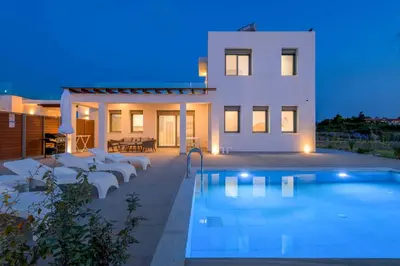 a villa with a swimming pool in front of a house at Villa Panaxia Votsalo in Theologos