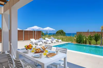 a patio with a table and chairs next to a swimming pool at Villa Panaxia Kohille in Theologos