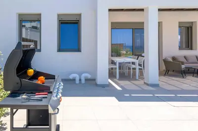 a barbecue on a patio with tables and chairs at Villa Panaxia Kohille in Theologos