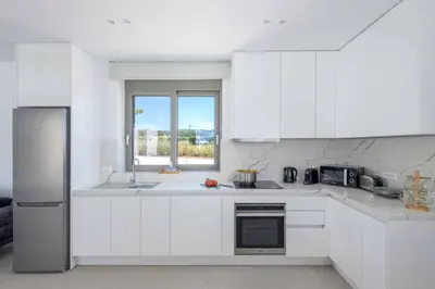 a white kitchen with white cabinets and a window at Villa Panaxia Kohille in Theologos