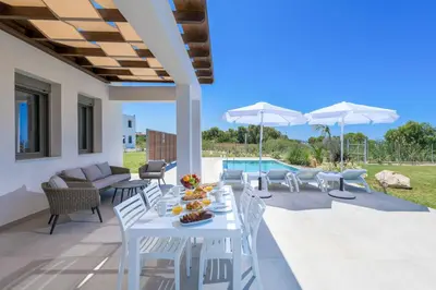 a white table and chairs on a patio with a pool at Villa Panaxia Keema in Theologos