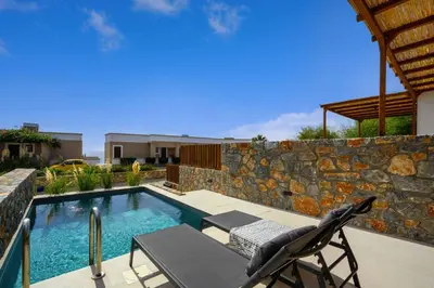 a swimming pool with a chair next to a stone wall at Villa Kiotari Star in Kiotari