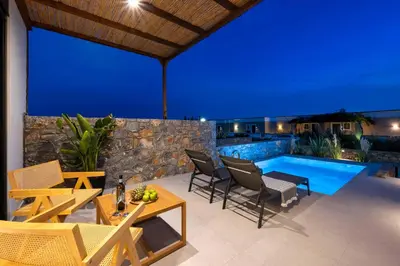 a patio with chairs and a pool at night at Villa Kiotari Star in Kiotari