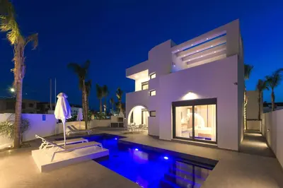 a large white house with a swimming pool at night at Villa Evelia in Ialyssos