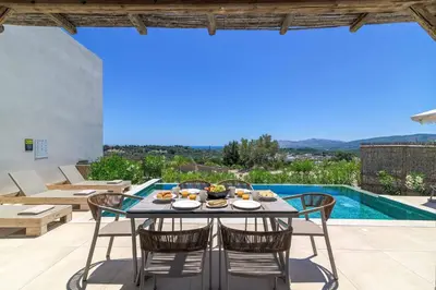 a dining table with chairs on a patio with a pool at Massari Hills Villa 9 in Malona Village