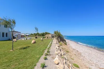 a beach with rocks and a house and the ocean at Villa Panaxia Akte in Theologos