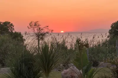 a sunset over the ocean with the sun in the horizon at Villa Panaxia Akte in Theologos