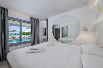 a bedroom with a large white bed and a mirror at Villa Pefko in Gennadi