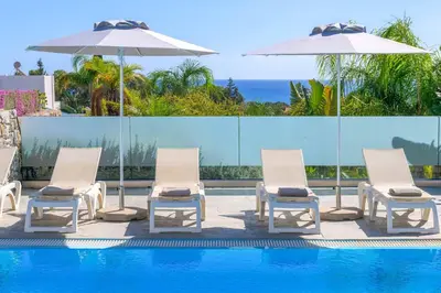 a group of chairs and umbrellas next to a pool at Villa Pefko in Gennadi