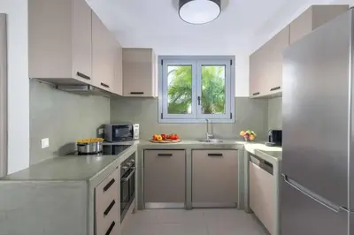 a large kitchen with white cabinets and a window at Villa Pefko in Gennadi