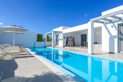 a villa with a swimming pool and an umbrella at Villa Pefko in Gennadi