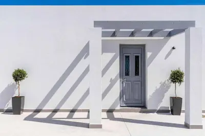 a white building with a door and two potted plants at Villa Damaskina in Gennadi
