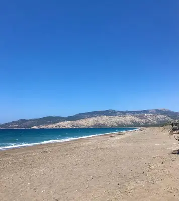a beach with the ocean and mountains in the background at Charming Cottage on the sea turtle beach in Apolakkiá