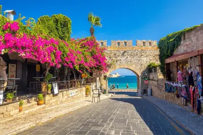 an alley in the city of dubrovnik with pink flowers at 400 Steps Apartment in Rhodes Town