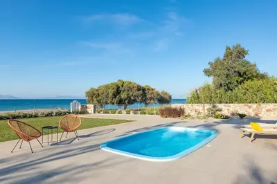 a swimming pool with two chairs and a table at KYRA beachfront house in Theologos Rhodes in Theologos
