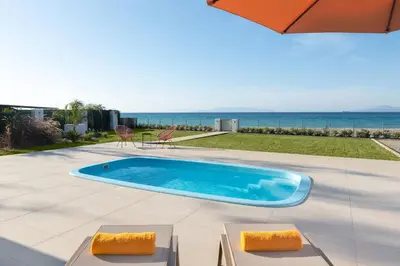 a swimming pool on a patio with the ocean in the background at KYRA beachfront house in Theologos Rhodes in Theologos