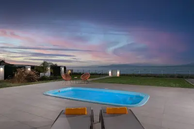 a swimming pool on a patio with two chairs at KYRA beachfront house in Theologos Rhodes in Theologos