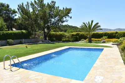 a large swimming pool in a yard with a garden at Villa Paradisos Archangelos in Archangelos