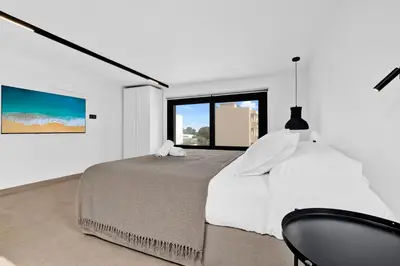 a white bedroom with a bed and a chair at San Marino Luxury Suites #3 in Asgourou