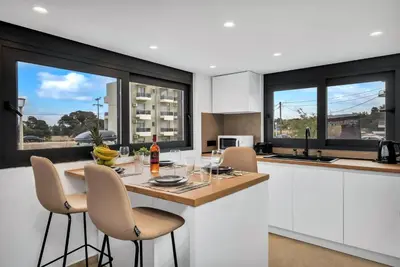 a kitchen with white cabinets and a table with chairs at San Marino Luxury Suites #3 in Asgourou