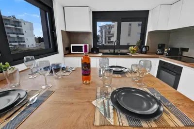 a wooden table with plates and wine glasses on it at San Marino Luxury Suites #3 in Asgourou