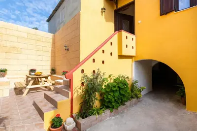 a yellow building with a staircase next to a table at Casa Medievale in Rhodes Town