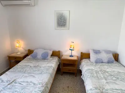 two beds in a room with two lamps on tables at Maison authentique avec grande terrasse in Kritinía
